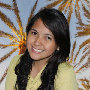 Personal photo of Jellene with a big smile under a tropical back drop of palms at sun set