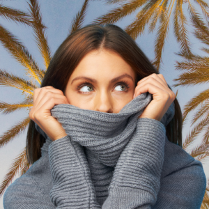 Girl hiding in turtle neck sweater with tropical back ground